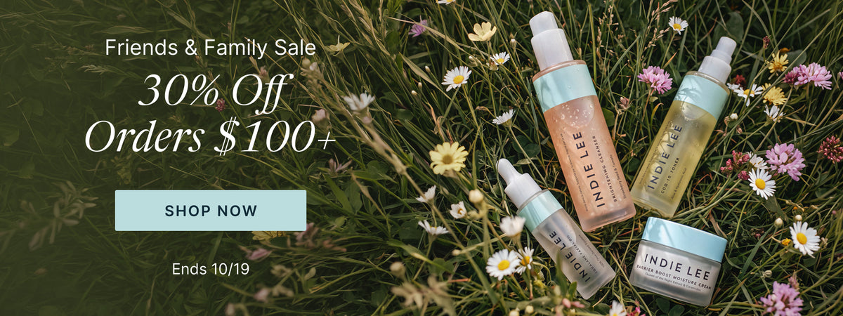 Bottles of Indie Lee skincare products placed on a grassy field with daisies, next to promotional text reading 'Friends and Family Sale - 30% Off Orders $100+'