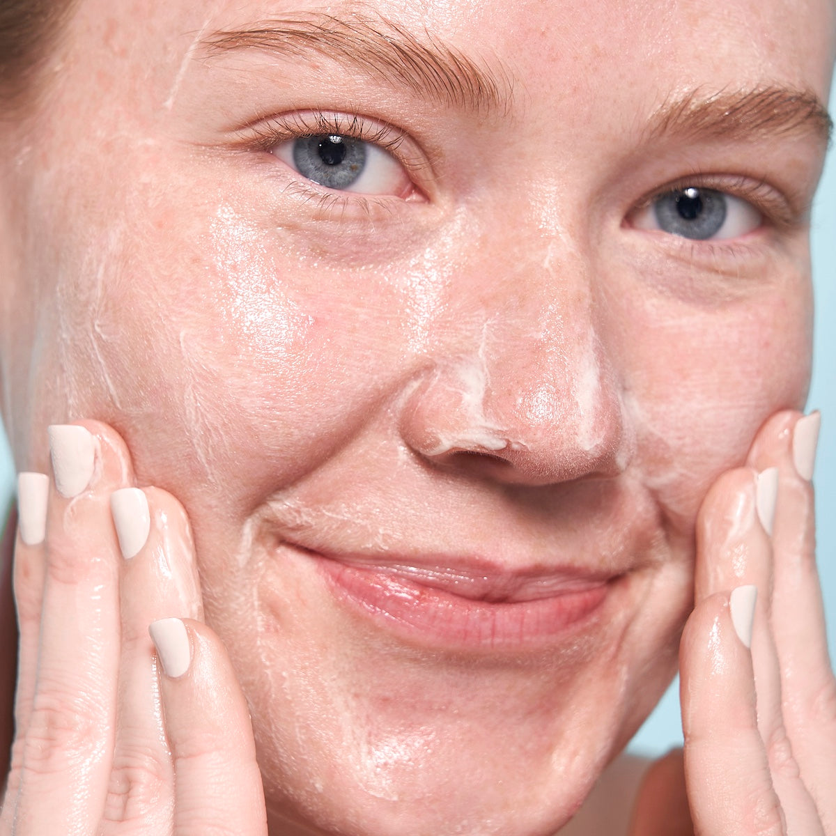 Woman applying Indie Lee Ceansing Balm to her face