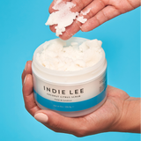 Woman scooping Indie Lee Coconut Citrus Body Scrub onto her hand