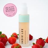 Bottle of Indie Lee Brightening Cleanser Balm on a white background with strawberries