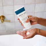 Woman dispensing Indie Lee Sleep Body Wash into her hand