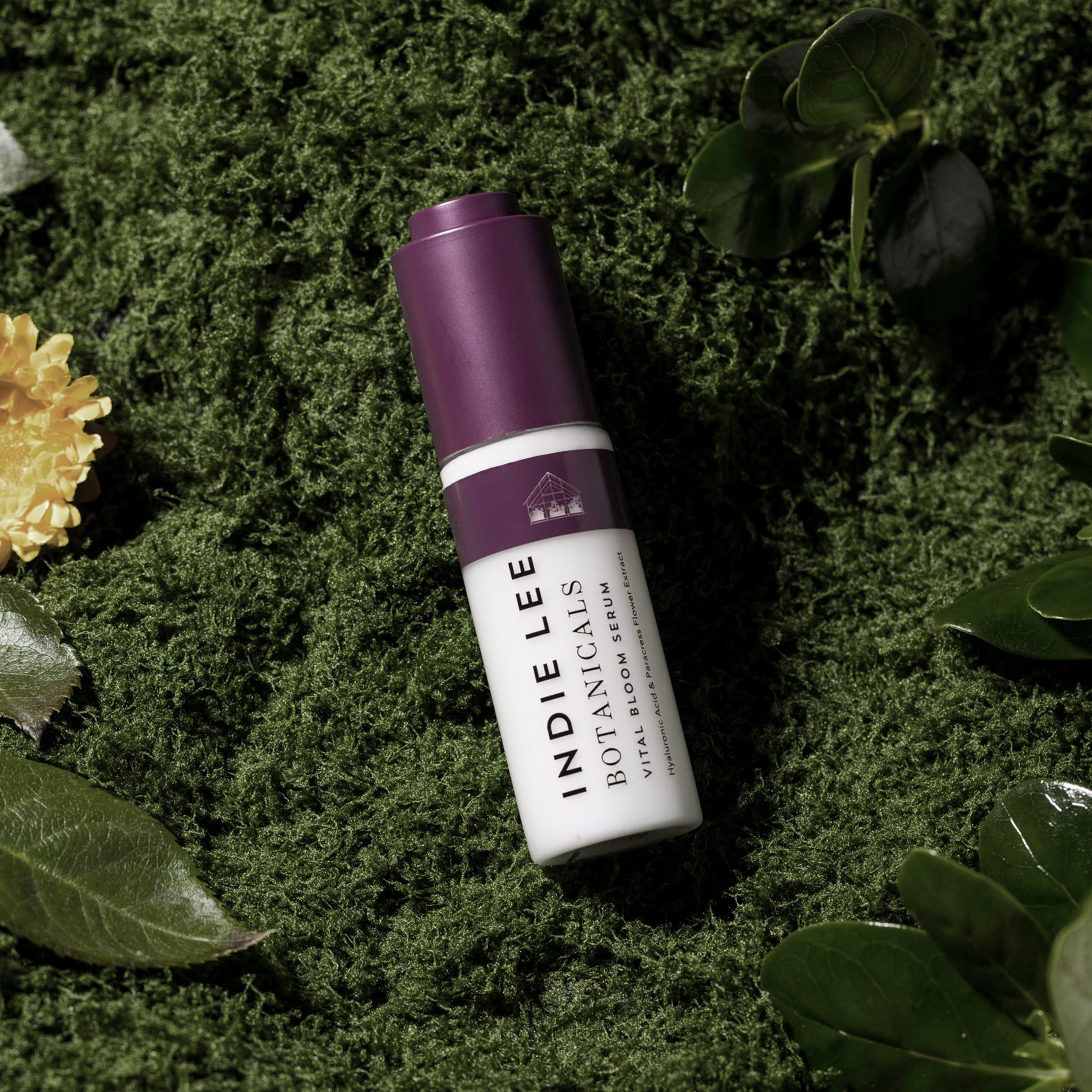 Indie Lee Botanicals Vital Bloom Serum bottle on a green leafy background