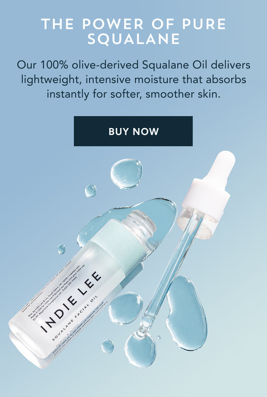 Open bottle of Indie Lee Squalane Facial Oil with drops of product dispensed from applicator