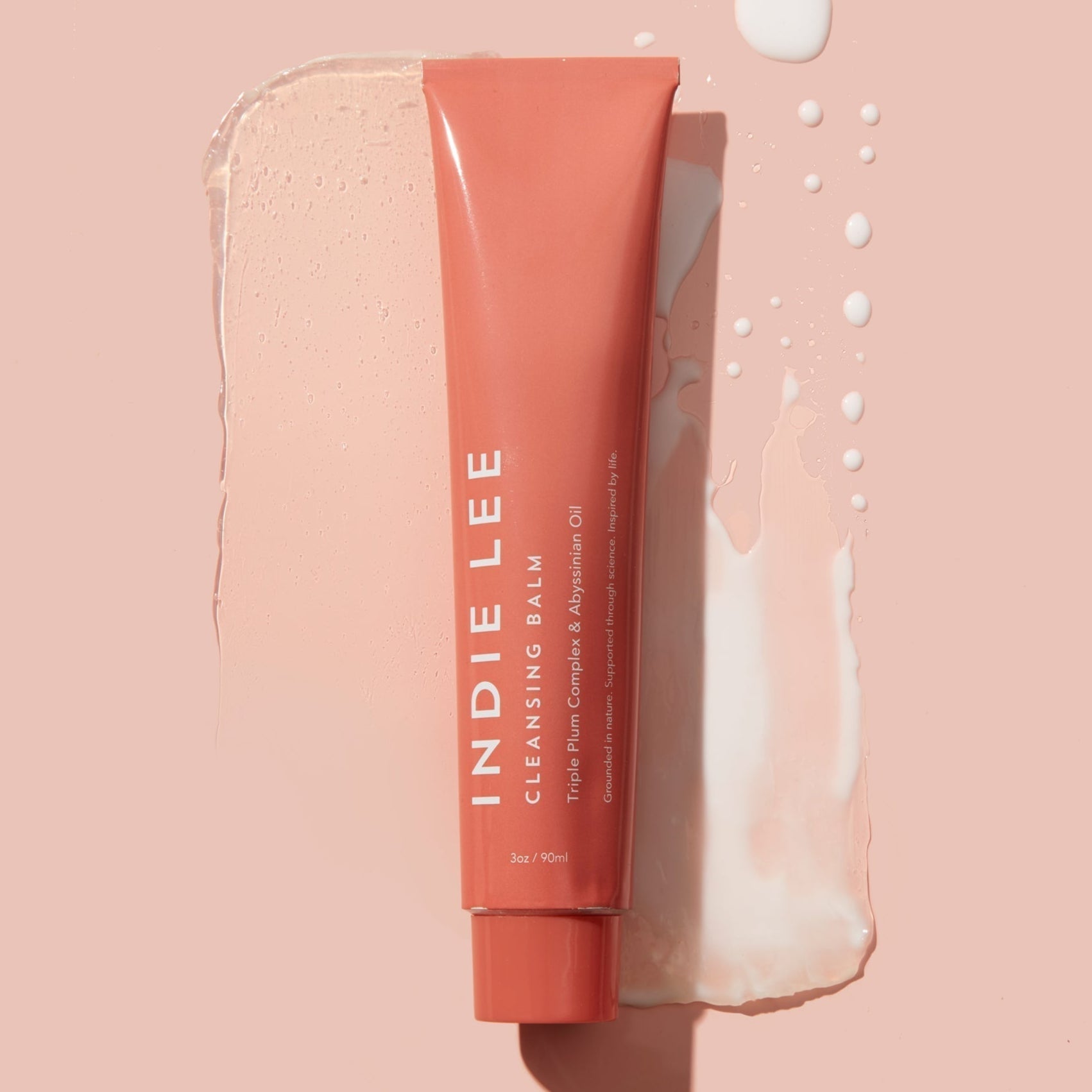 Indie Lee cleansing balm tube on a pink background