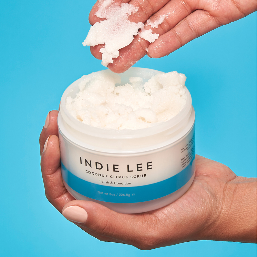 Woman scooping Indie Lee Coconut Citrus Body Scrub onto her hand