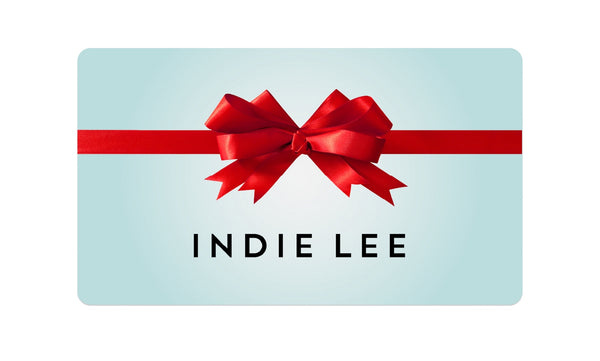 Gift card with a red bow and 'Indie Lee' branding on a light blue background