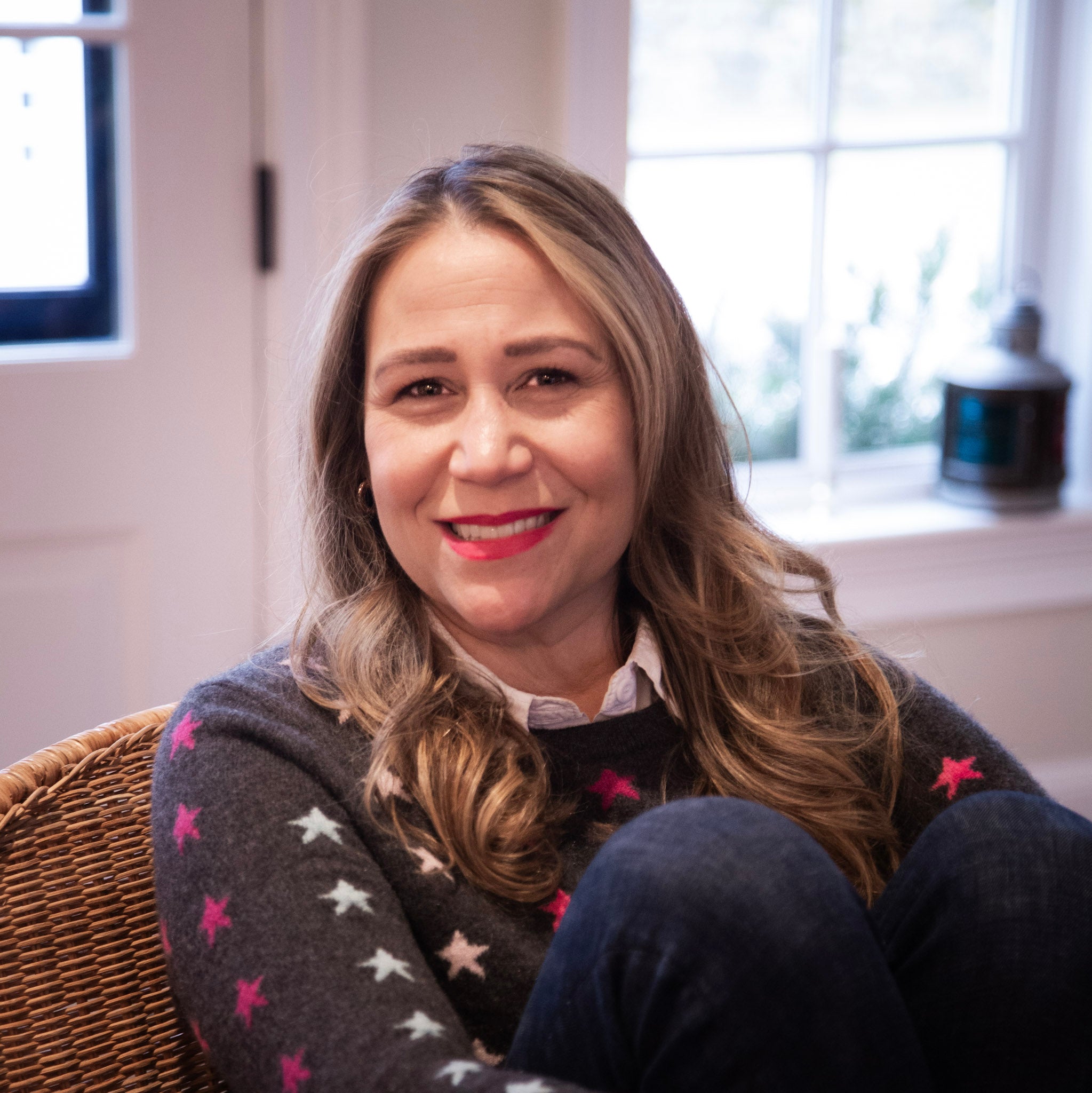 Indie Lee sitting indoors wearing a dark sweater with star patterns