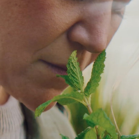 Indie Lee smelling a bundle of fresh mint