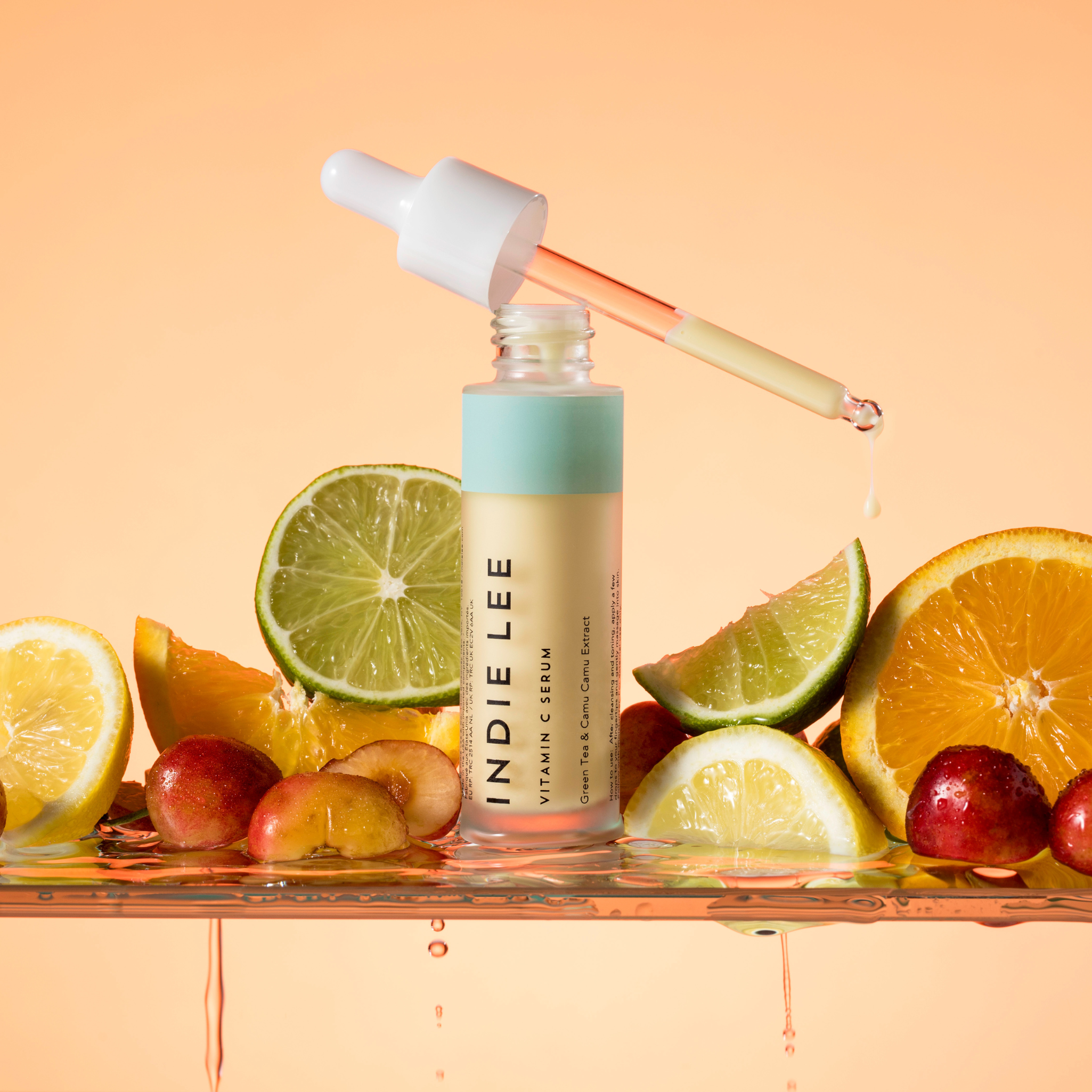 An open bottle of Indie Lee Vitamin C Serum, with a sample of product dispensing from the dropper applicator